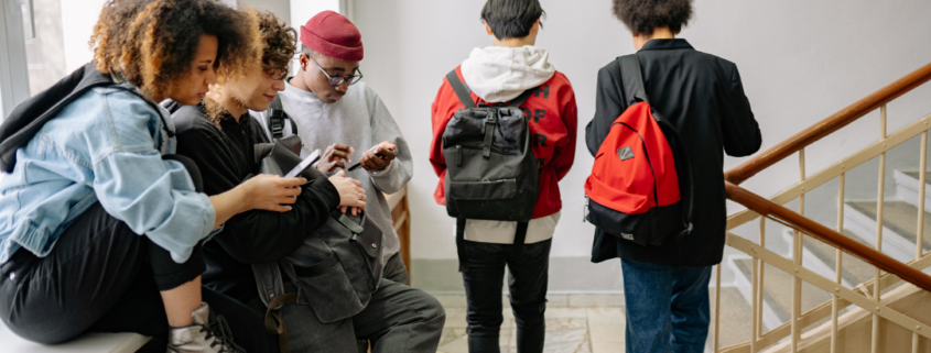 A group of five students sitting near a staircase